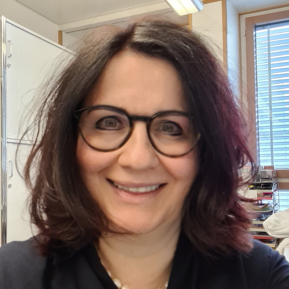 Portrait Prof. Dr. Zsuzsanna Varga, weiblich lesbare, hellhäutige Person mit Brille, schwarzen, mittellangen Haaren, schwarzem Oberteil