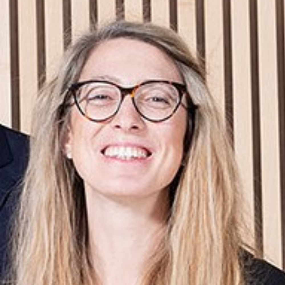 Portrait Prof. Dr. Elisabetta Fiocchi Malaspina, weiblich lesbare, hellhäutige Person mit langen, blonden Haaren und schwarzem Oberteil